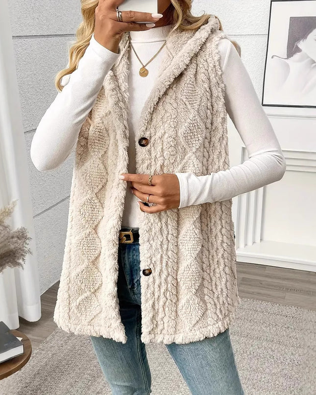 Person wearing a beige cable knit vest in a room with decor elements.