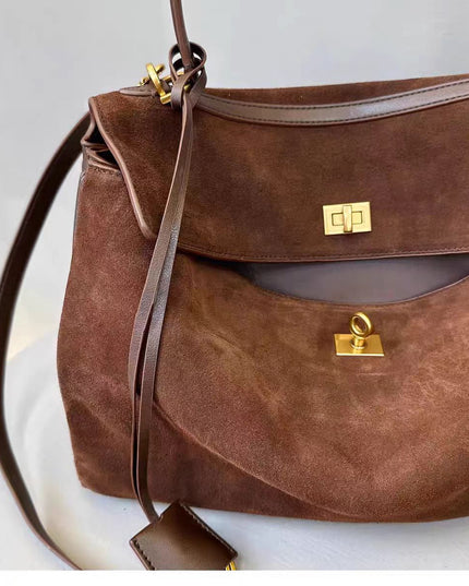 Brown leather handbag with gold hardware on a light background