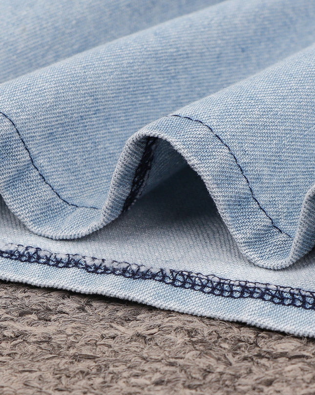 Close-up of blue denim fabric with visible stitching on a textured surface