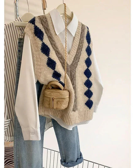 Beige sweater vest with blue diamond pattern over a white shirt and blue jeans, paired with a small brown handbag.