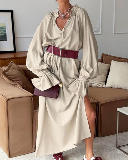 Woman wearing a beige dress with a maroon belt and shoes in a living room setting.