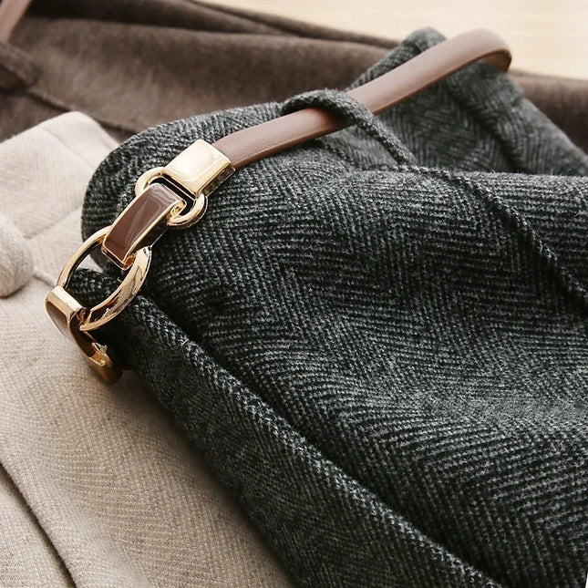 Close-up of a textured fabric with a gold and brown leather strap.