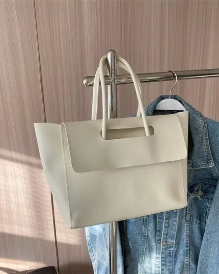 Beige handbag hanging on a rack with a denim jacket