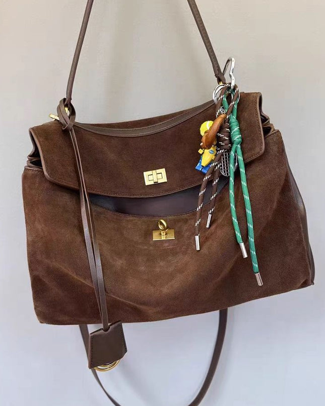 Brown suede handbag with decorative keychain on a light background