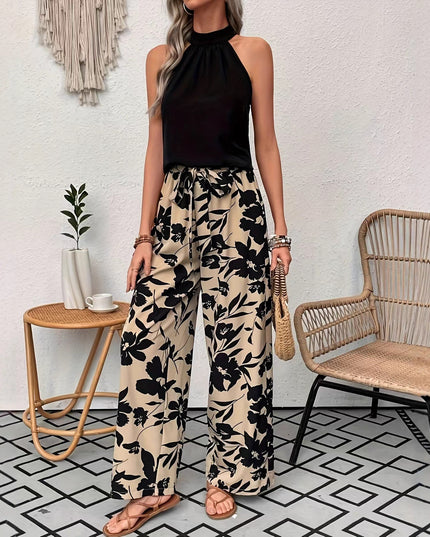 Woman wearing a black halter top and floral pants in a room with a white wall and geometric floor pattern.