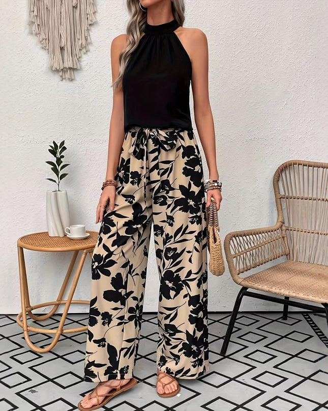 Woman wearing a black halter top and floral pants in a room with a white wall and geometric floor pattern.