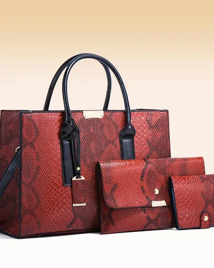 Red snakeskin pattern handbag set with matching wallet and pouch on a beige background