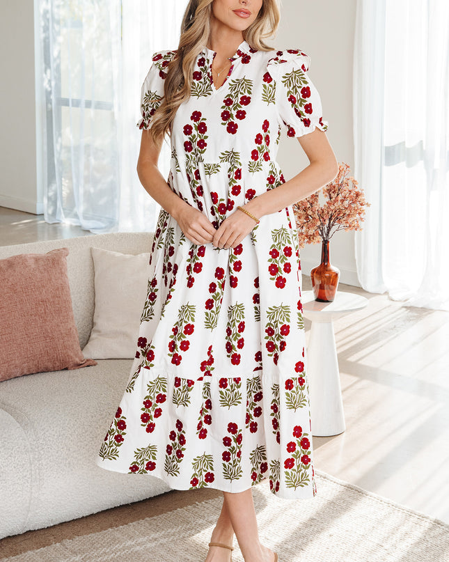 Woman wearing a white dress with red floral pattern in a living room.
