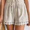 Beige shorts with lace trim worn by a person on a neutral background
