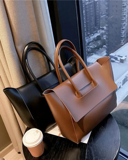 Two handbags, one black and one brown, on a surface with a cityscape view through a window.