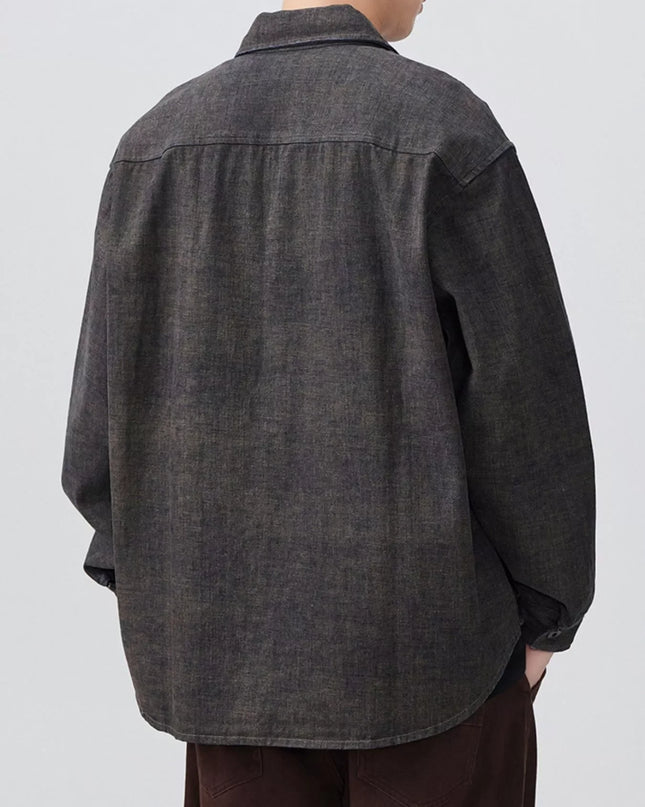 Person wearing a dark denim shirt on a plain background