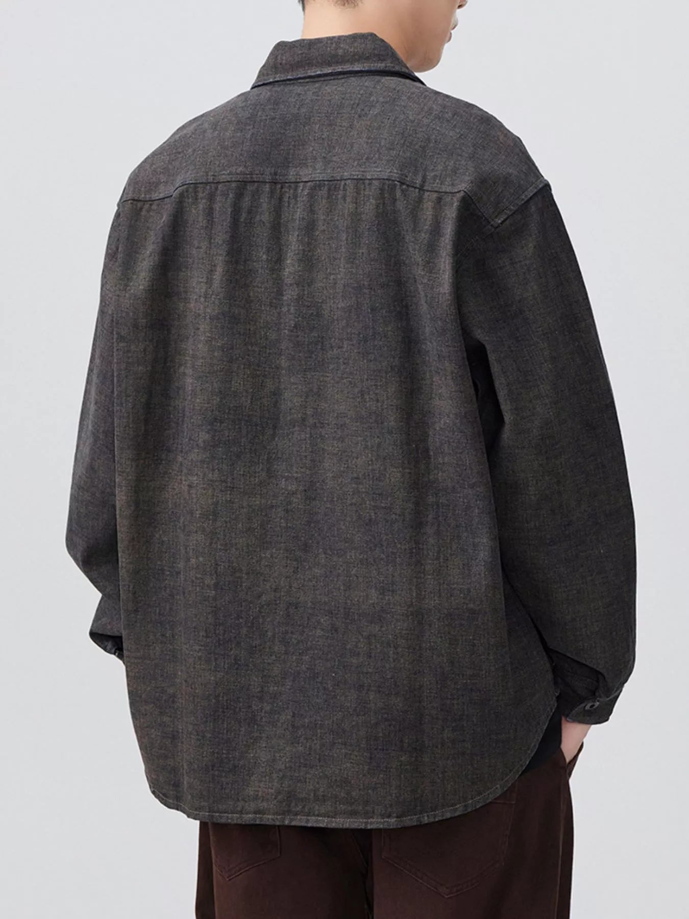 Person wearing a dark denim shirt on a plain background