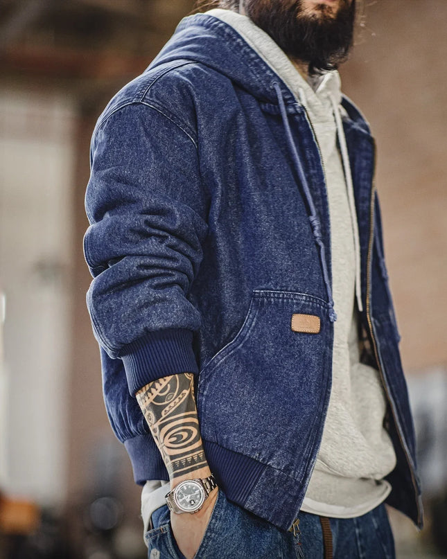 Person wearing a blue denim jacket with a visible brand logo, standing indoors.