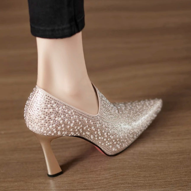 High-heeled shoe with pearl embellishments on a wooden floor