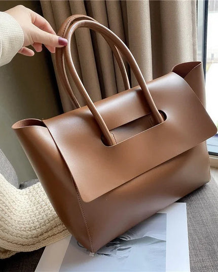 Brown handbag held by a person with a neutral background
