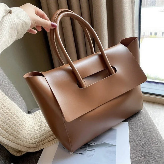 Brown handbag held by a person with a neutral background