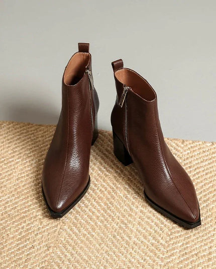 Pair of brown leather ankle boots on a textured surface with a neutral background