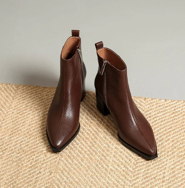 Pair of brown leather ankle boots on a textured surface with a neutral background