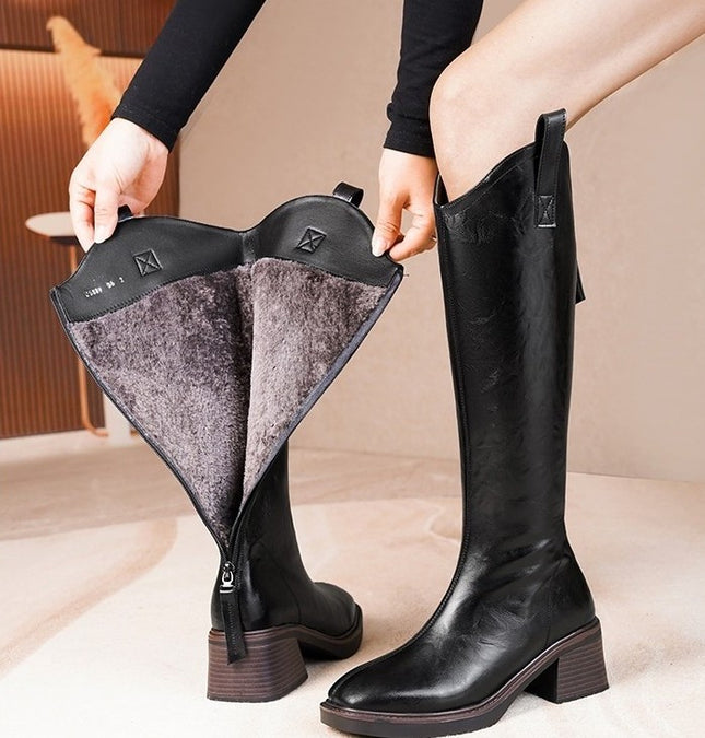 Black knee-high boots with a zipper being pulled open on a beige background