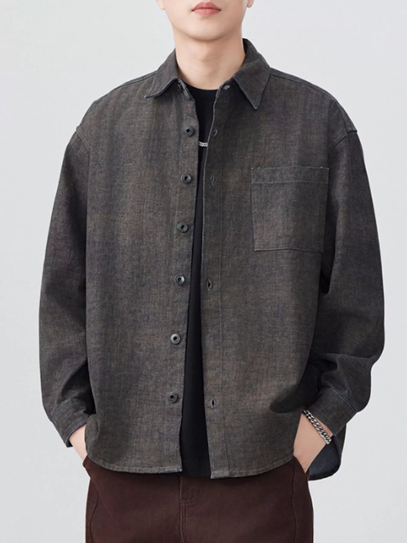 Person wearing a dark gray button-up shirt on a white background