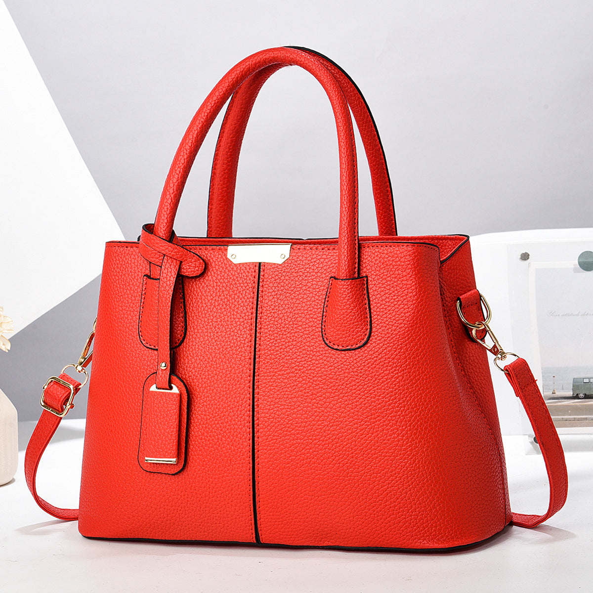 Red handbag with a strap on a light gray background