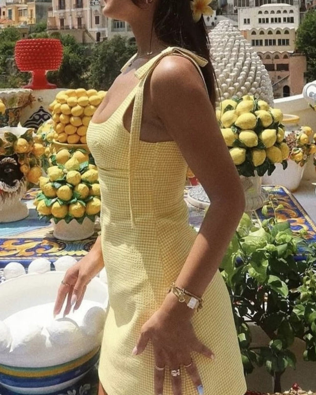 Woman in a yellow dress standing in front of lemon decorations and buildings.