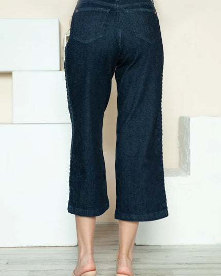 Dark blue jeans worn by a person standing against a neutral background