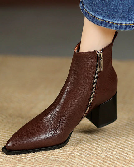 Brown leather ankle boot with a zipper on a textured surface