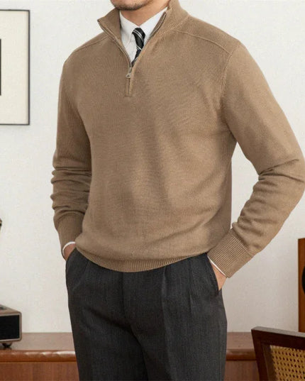 Man wearing a brown sweater and dark pants in a room with vintage decor.