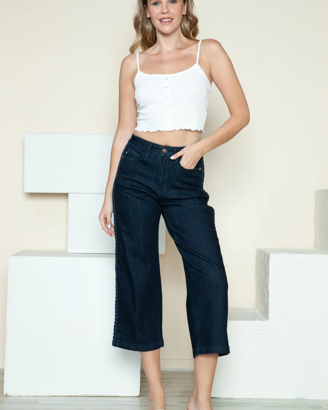 Woman wearing a white top and dark blue jeans against a light background