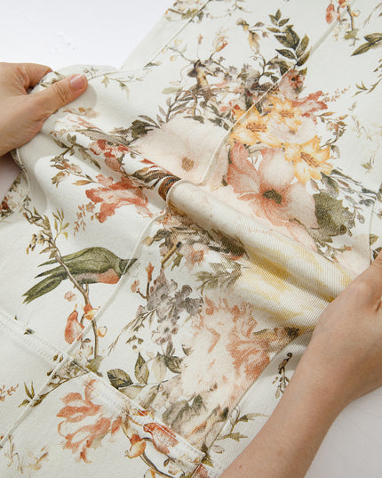 Floral fabric being held by hands on a white background
