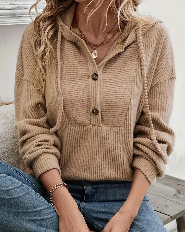 Person wearing a beige knitted cardigan with a neutral background