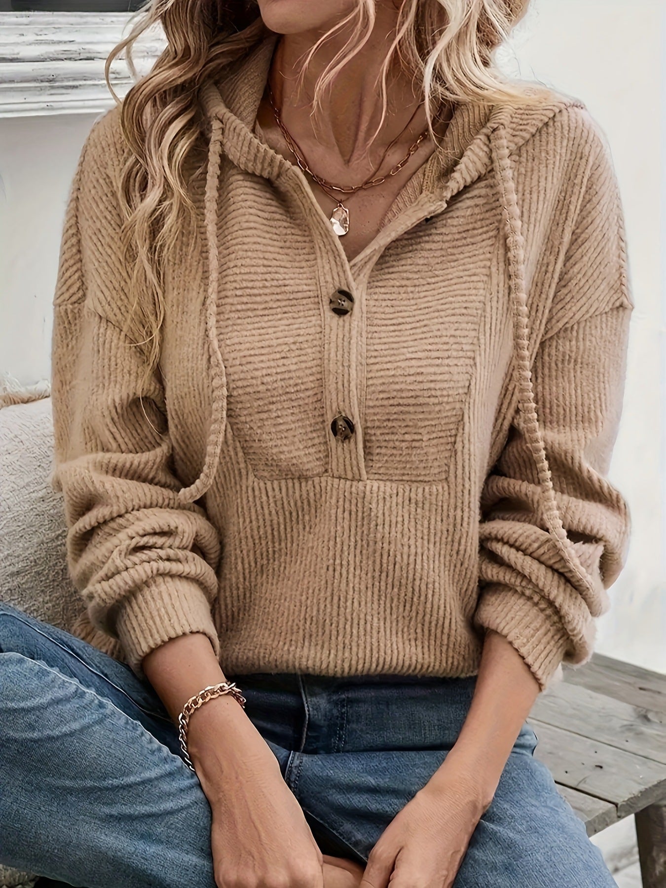 Person wearing a beige knitted cardigan with a neutral background