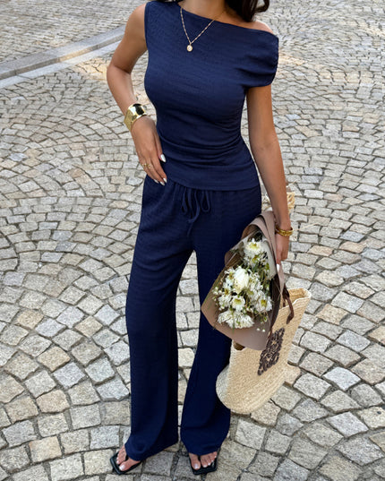 Woman in a navy blue outfit holding flowers on a cobblestone street