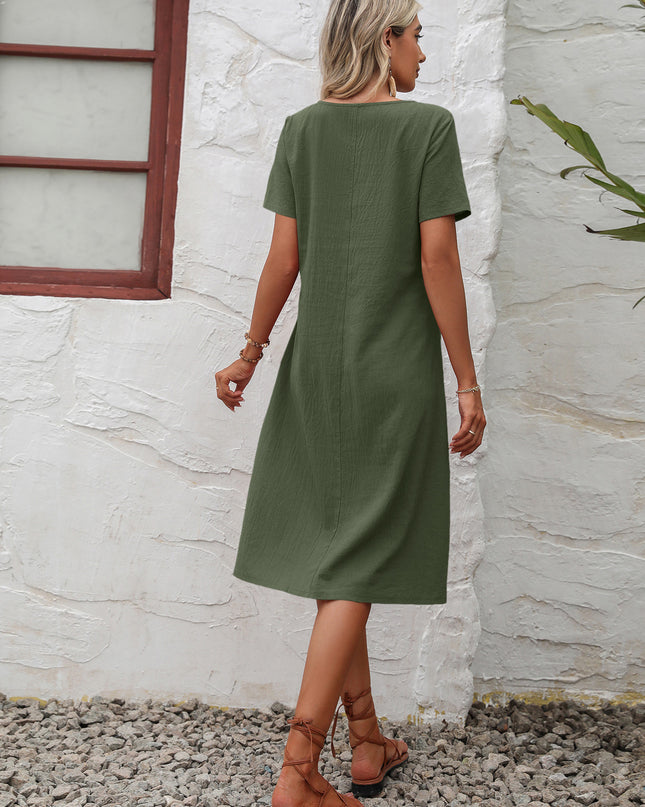 Woman wearing a green dress standing against a white wall.