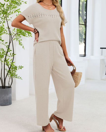 Woman in a beige outfit holding a straw bag in a bright room with plants.