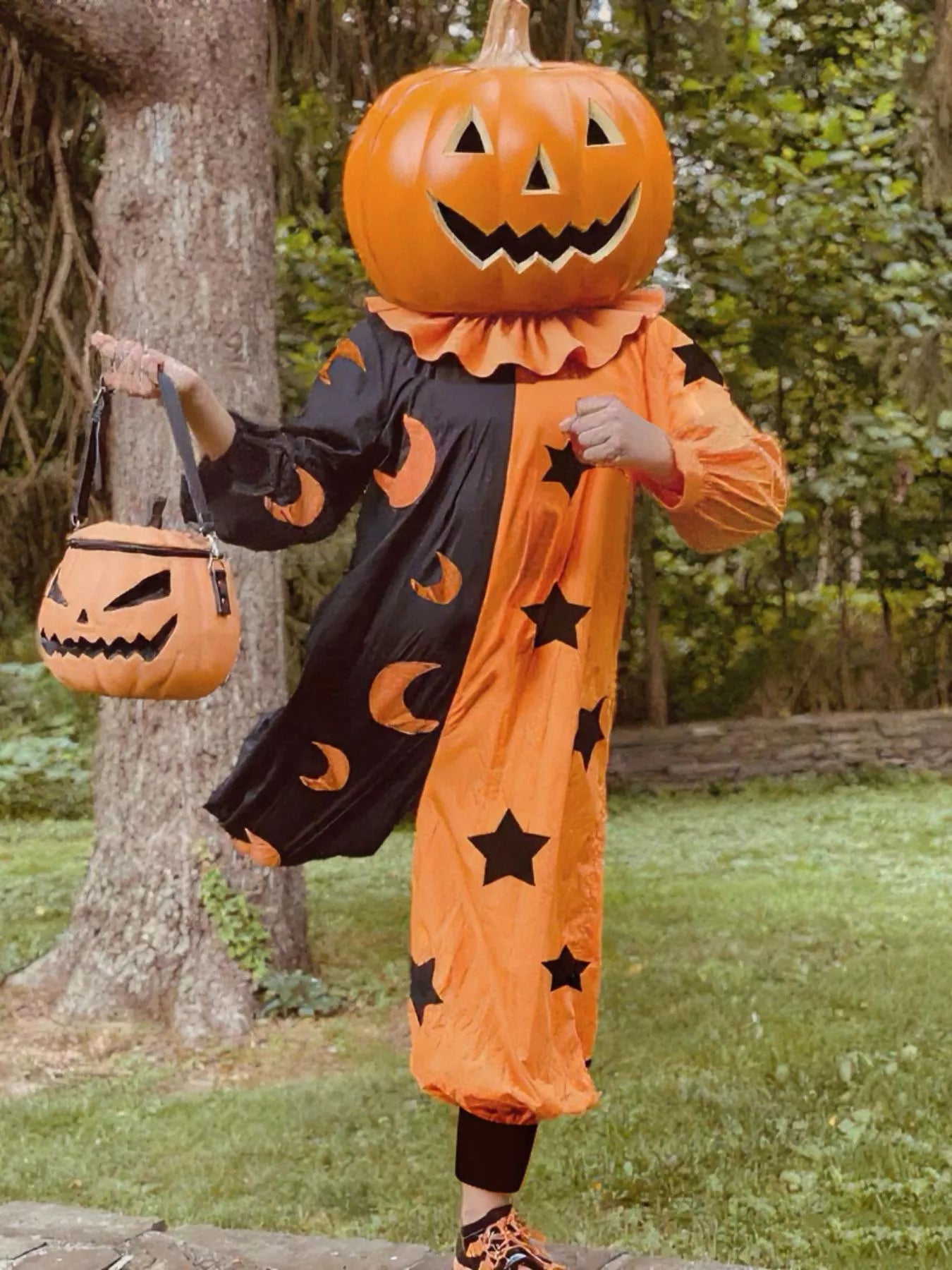 Person in a Halloween pumpkin costume with a tree and grass background