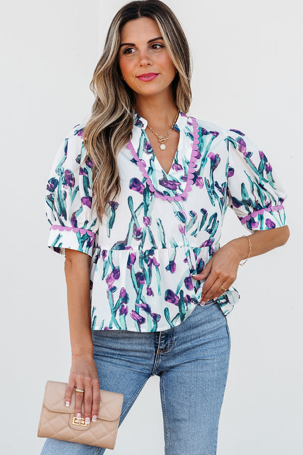 Woman wearing a floral blouse and jeans with a beige clutch against a white background