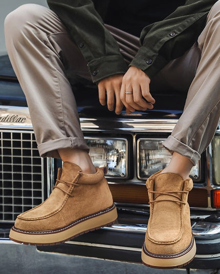 Person wearing brown suede boots sitting on a car bumper.