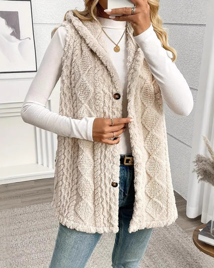 Woman wearing a beige cable knit vest in a room with decor elements.