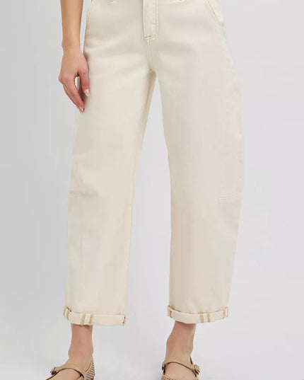 Person wearing light-colored jeans and beige shoes on a plain background