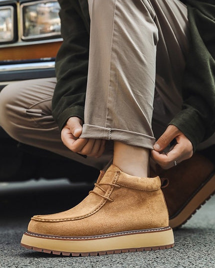 Person wearing tan suede boots with a blurred car in the background