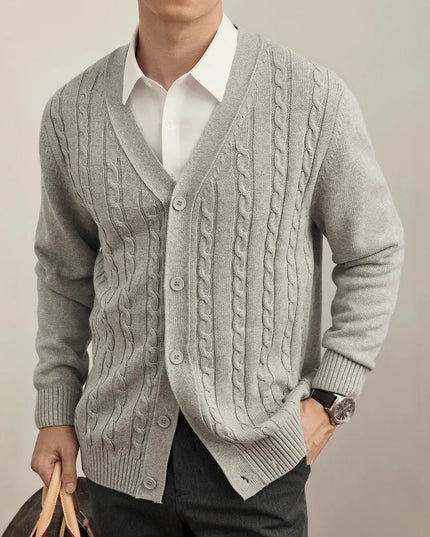 Man wearing a gray cable knit cardigan over a white shirt on a plain background