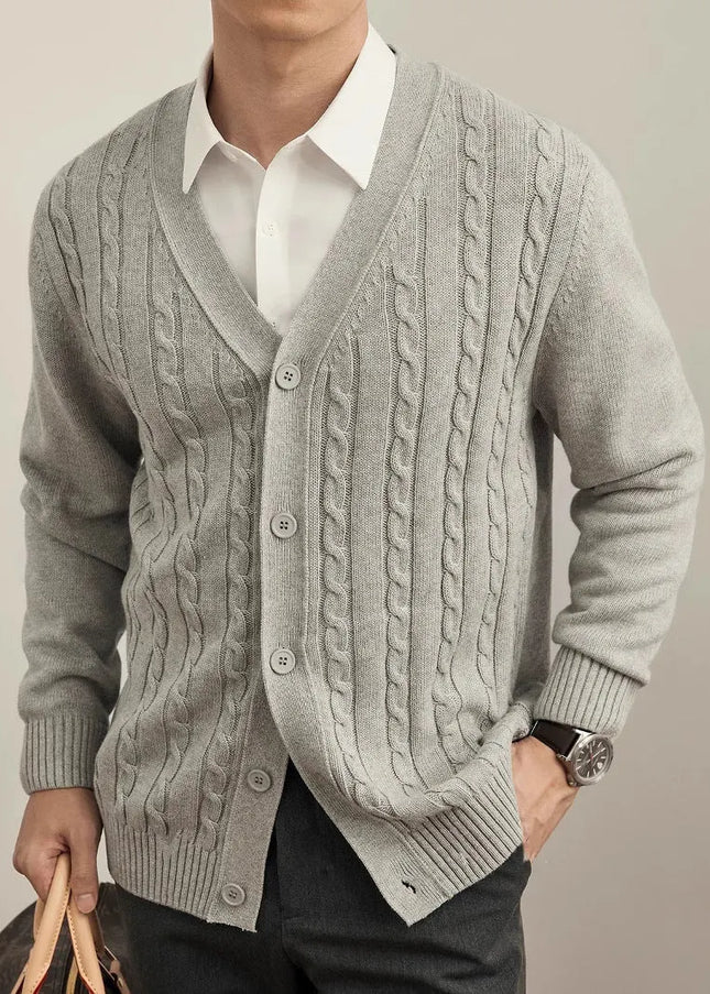 Man wearing a gray cable knit cardigan over a white shirt on a plain background