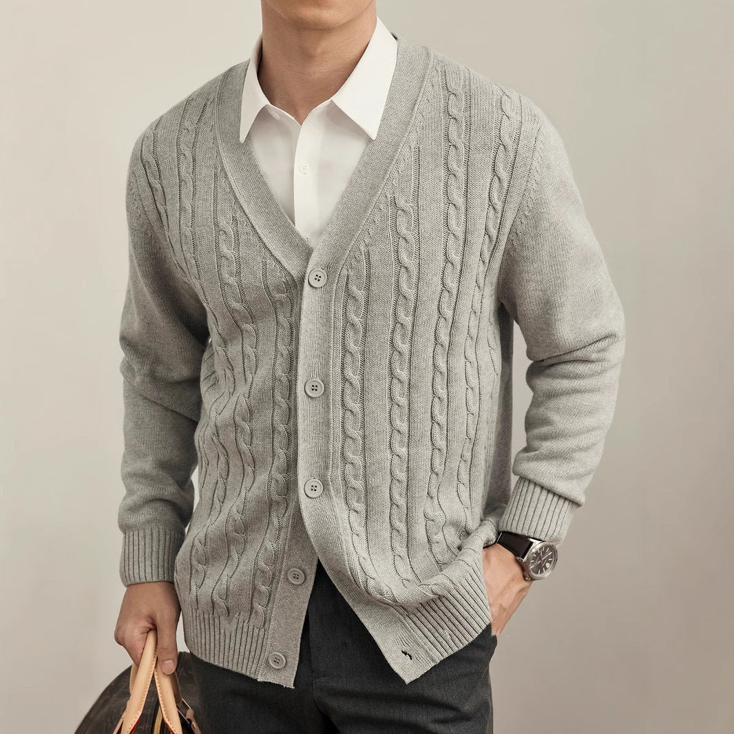 Man wearing a gray cable knit cardigan over a white shirt on a plain background