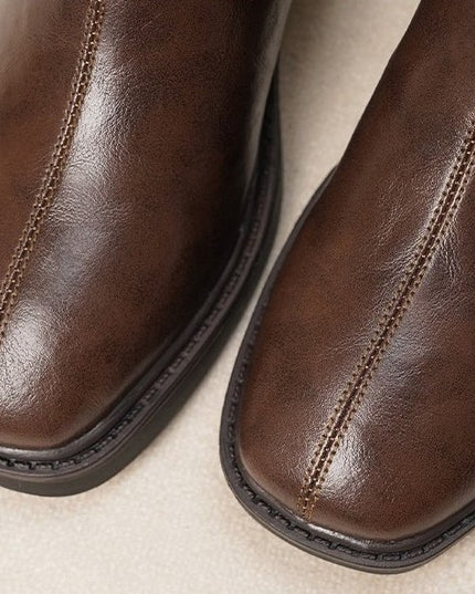 Close-up of brown leather boots on a beige background
