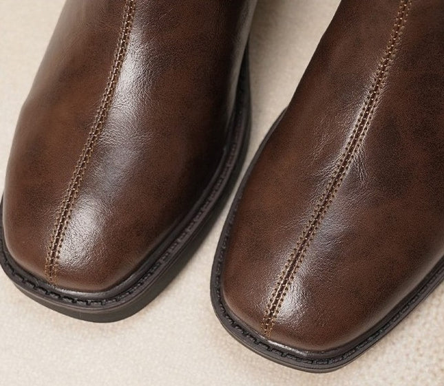 Close-up of brown leather boots on a beige background