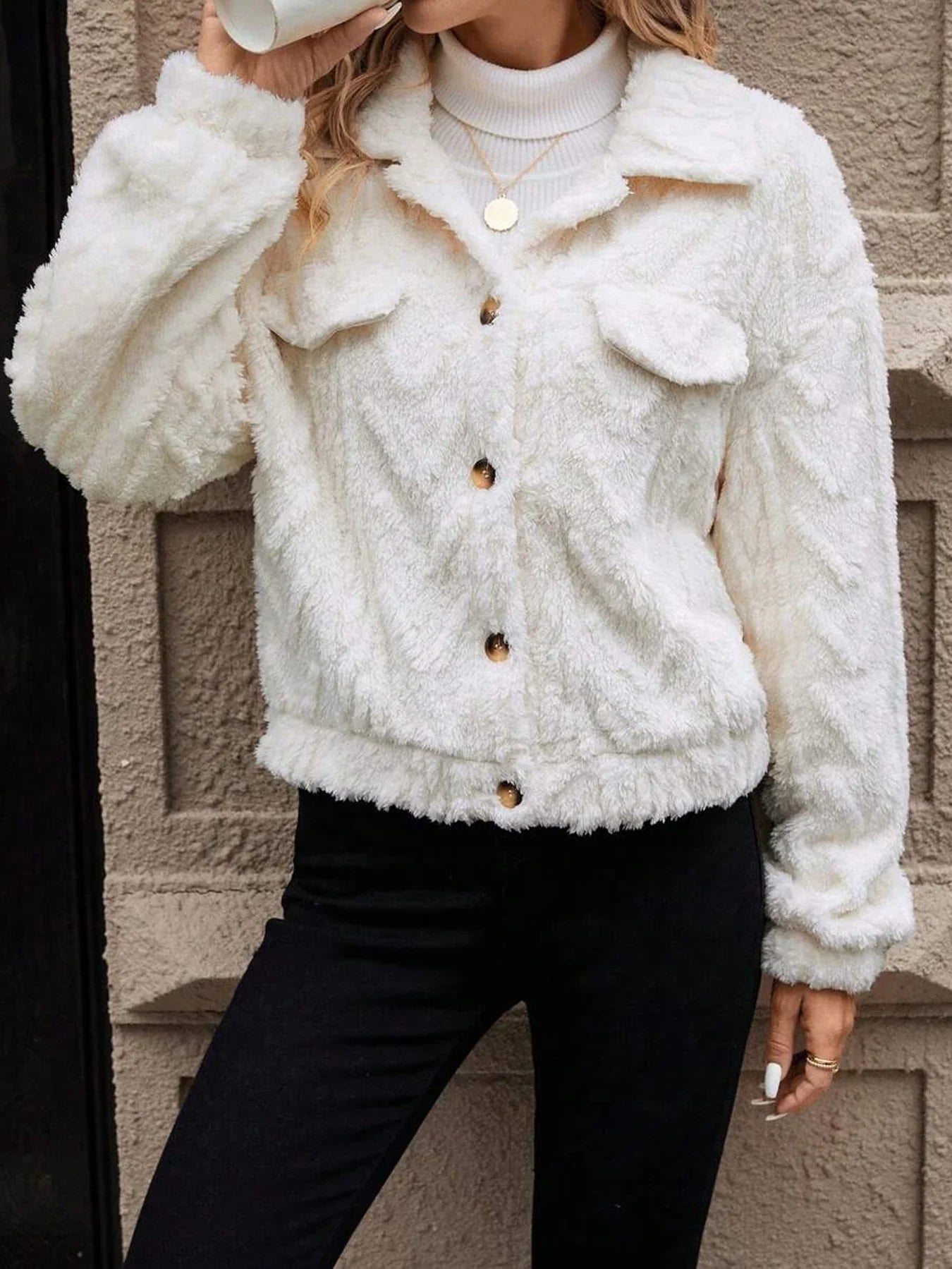 Person wearing a white fluffy jacket against a neutral wall.