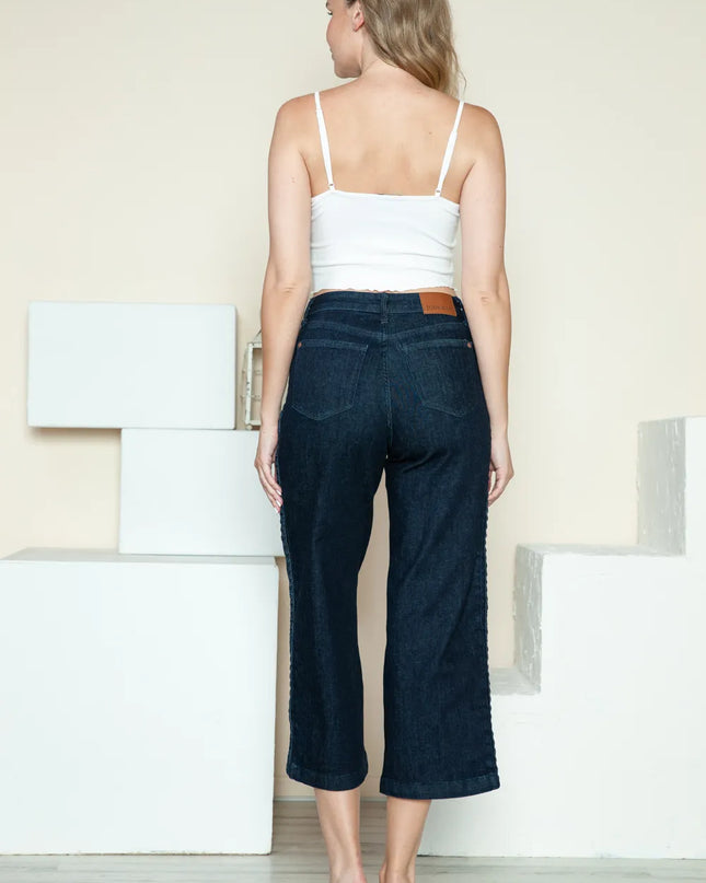 Woman wearing a white top and dark blue jeans standing on a staircase.