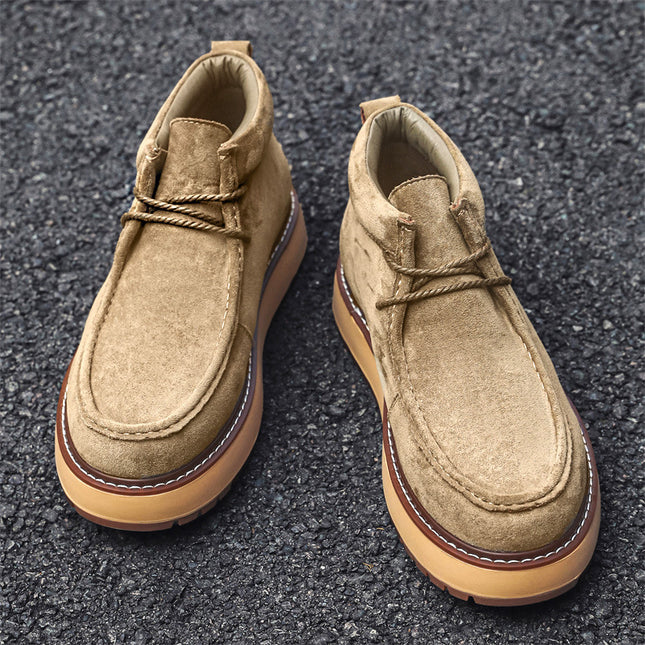 Pair of tan suede shoes on a dark asphalt surface